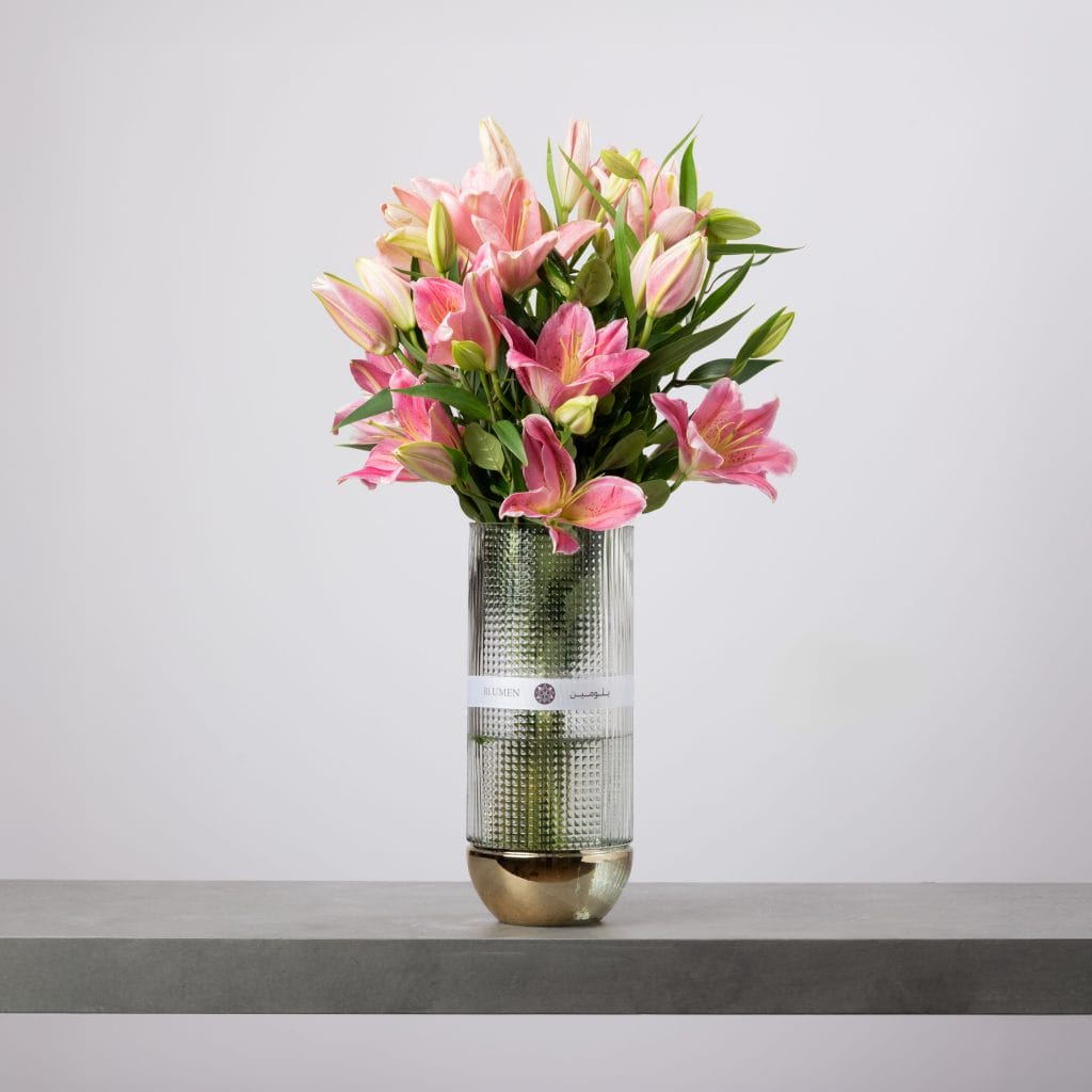 Pink lily arrangement in textured glass vase with gold base.
