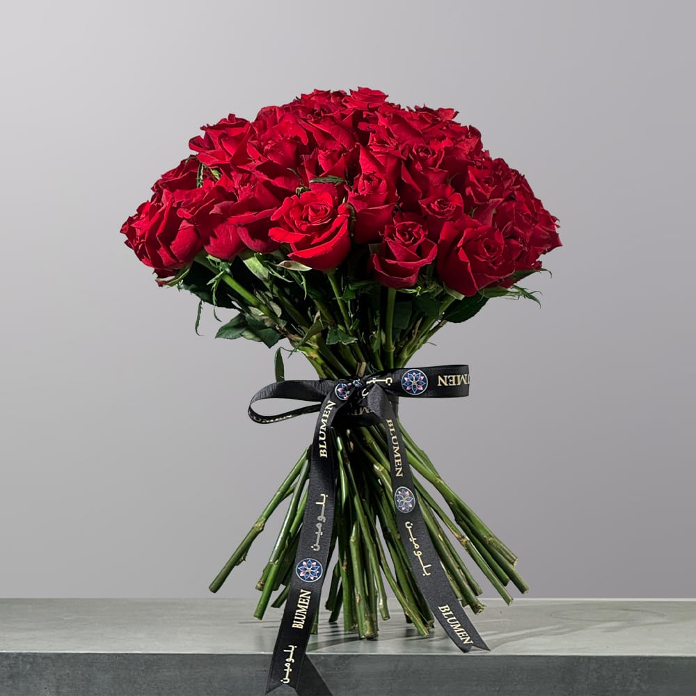 The Devoted Whisper bouquet featuring elegant red roses arranged in a romantic floral design
