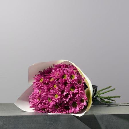 A hand-tied bouquet of vibrant violet chrysanthemums, elegantly wrapped in premium floral paper and finished with a decorative ribbon.