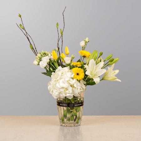 A graceful floral arrangement featuring premium blooms, delicate seasonal flowers, and fresh greenery, elegantly arranged in a decorative vase.