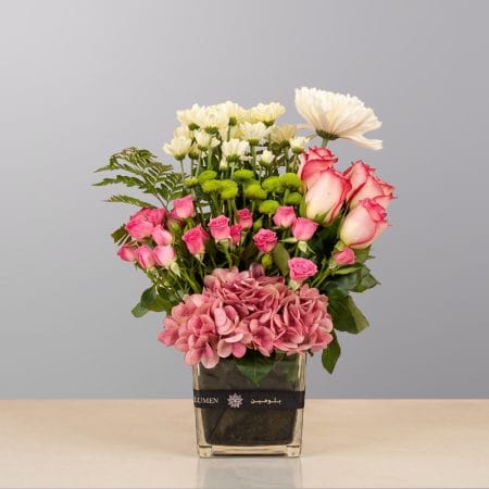 A refined floral arrangement featuring premium blooms, delicate seasonal flowers, and fresh greenery, elegantly arranged in a decorative vase.