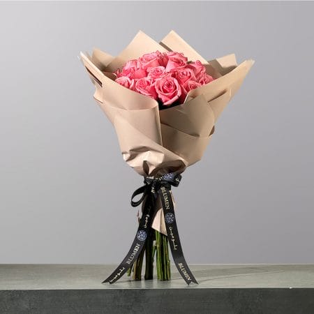 A luxurious hand-tied bouquet of pink roses, elegantly wrapped in premium floral paper and finished with a signature ribbon.
