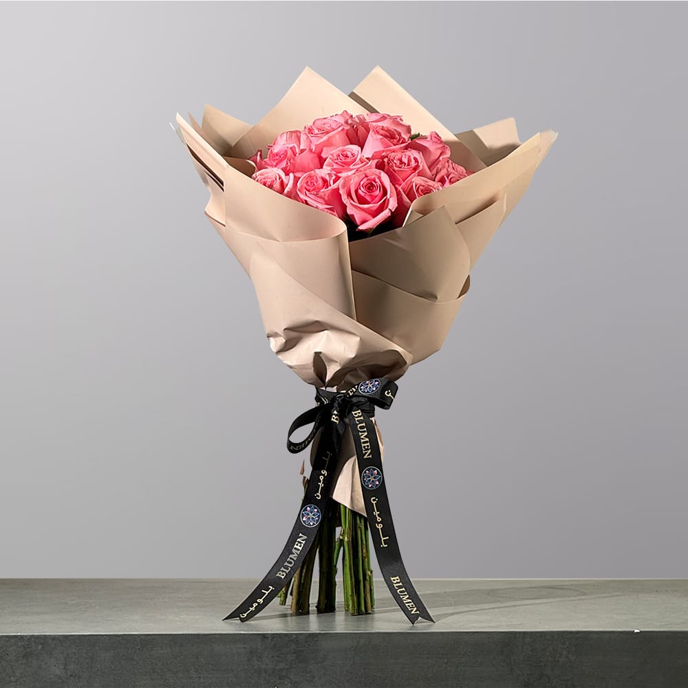 A luxurious hand-tied bouquet of pink roses, elegantly wrapped in premium floral paper and finished with a signature ribbon.