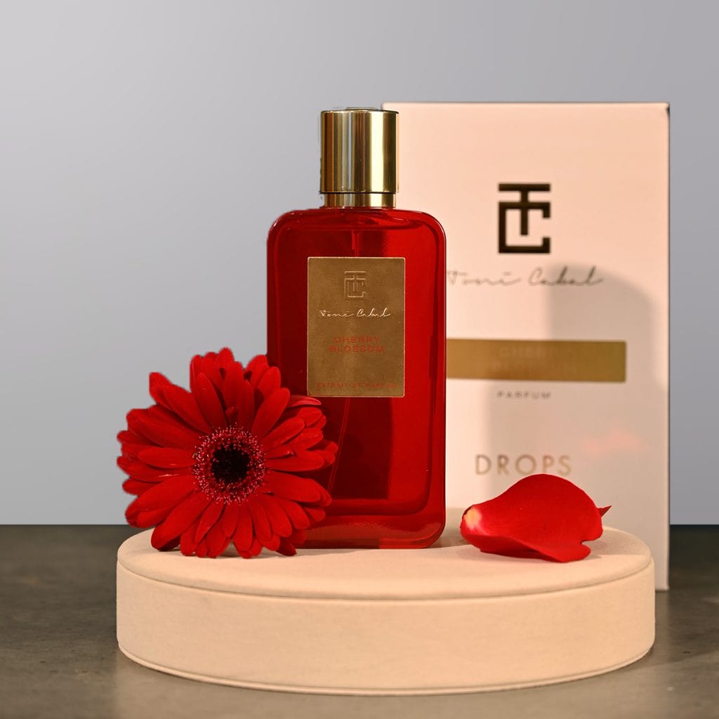 A perfume bottle by Drops with a flower next to it.