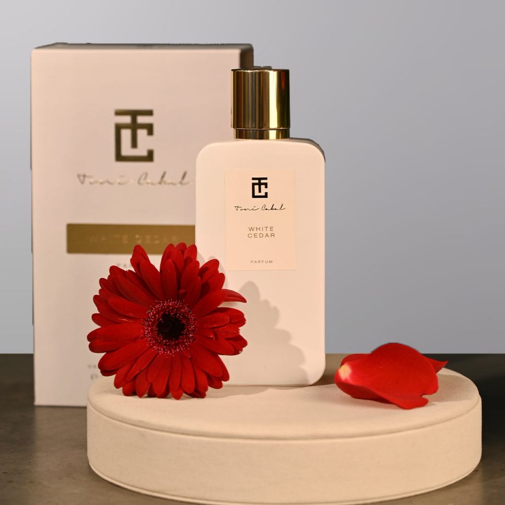 A perfume bottle by Drops with a flower next to it.